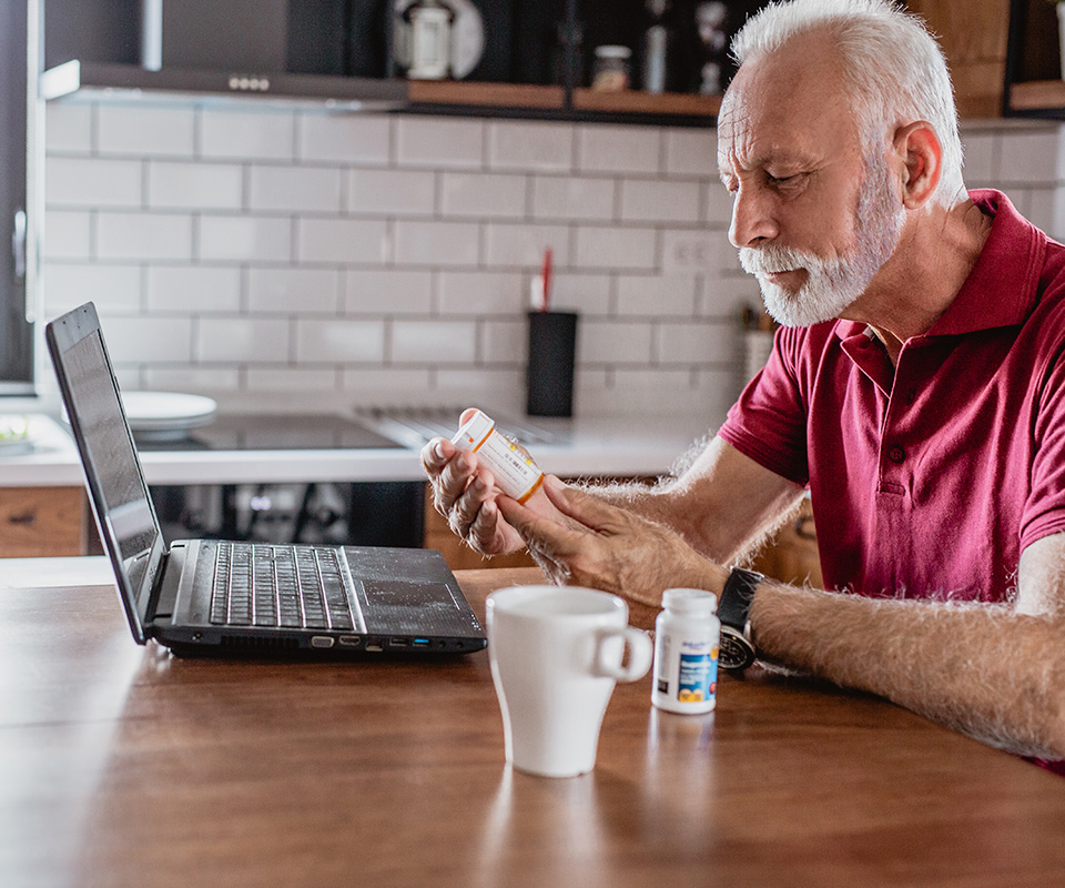 Searching online about medicine Man searching online holding a prescription bottle